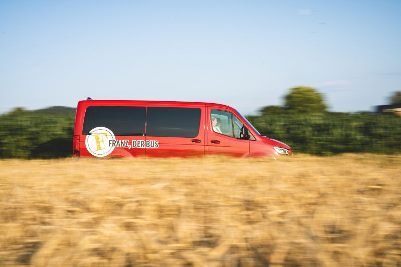 Franz, der Bus on Tour, im Vordergrund ist ein Weizenfeld zu sehen